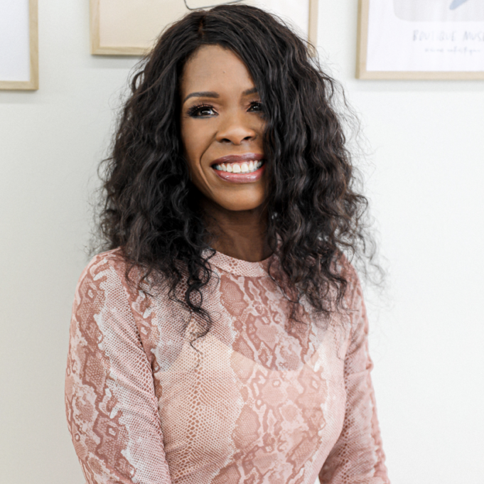 founder sitting down and smiling. She is wearing a rose colored dress